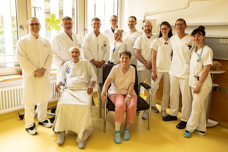 Zwölf Personen die nebeneinander im Patientenzimmer stehen